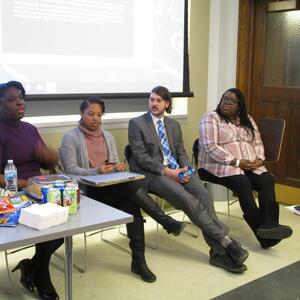 Four students in the front of a classroom discussing their research